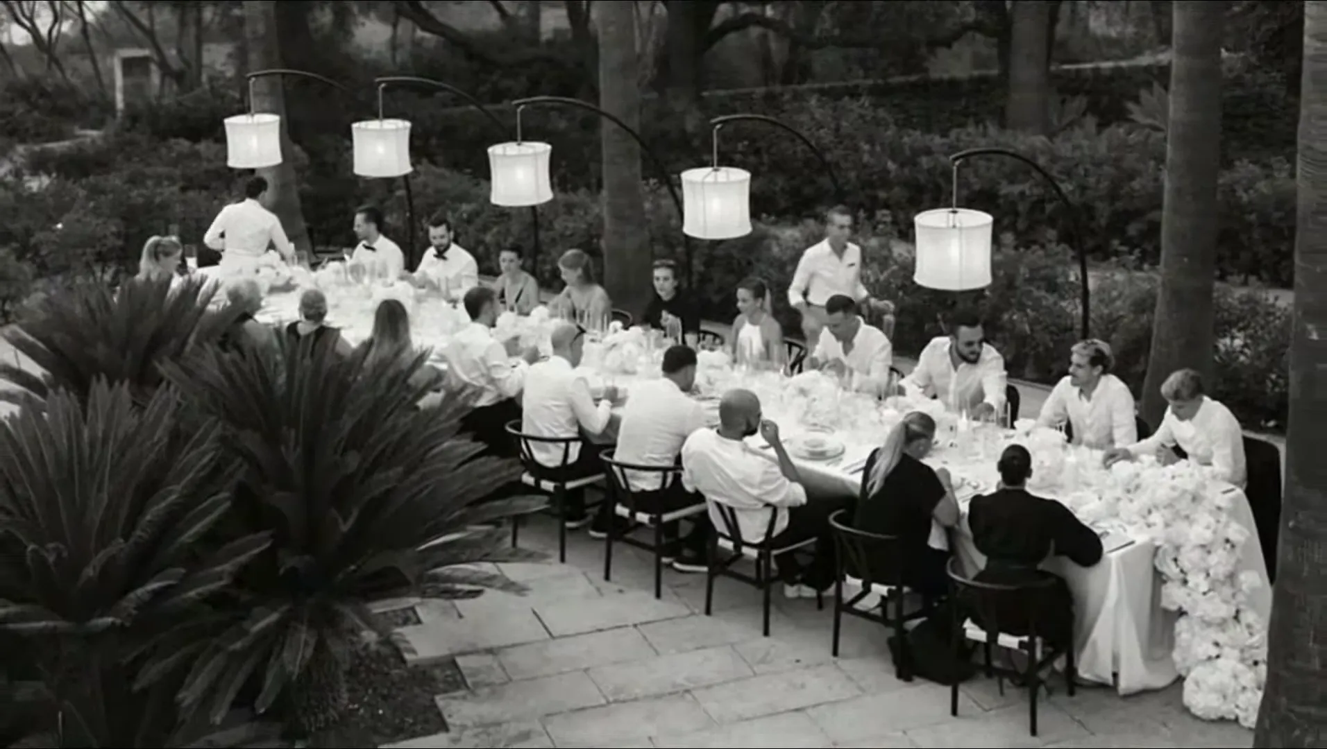 Lange Hochzeitstafel unter Lampions am Abend, Gäste beim Dinner