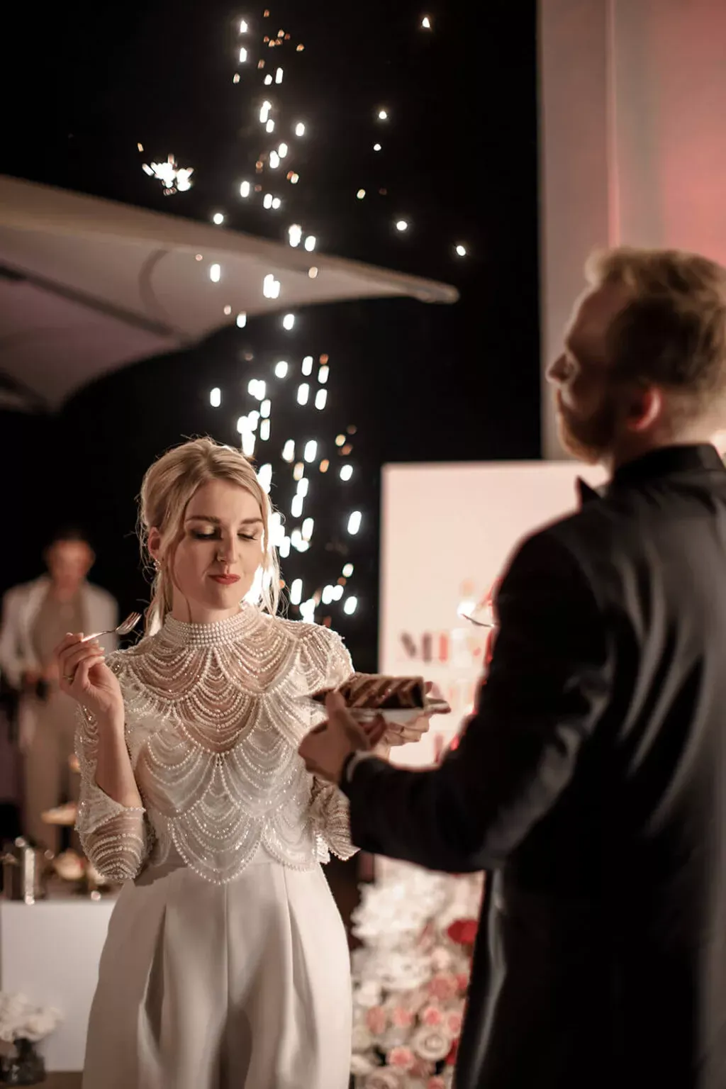 Bride and groom cutting the cake, sparklers in the background